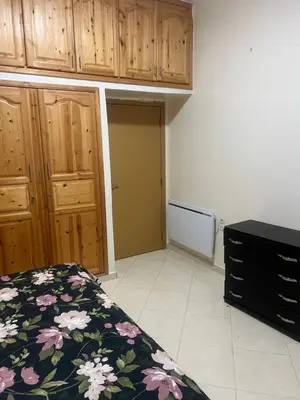 a bedroom with a bed and wooden cabinets at Appartement in Mohammedia