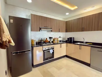 a kitchen with stainless steel appliances and wooden cabinets at Appartement de Luxe près du CFC et de l Hôpital Cheikh Khalifa in Casablanca