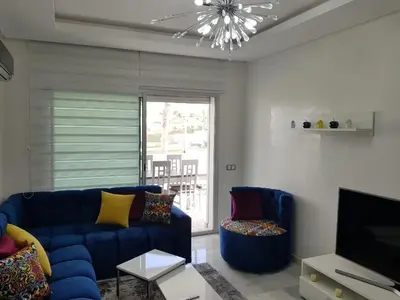 a living room with a blue couch and a television at Appartement pied sur mer in Mohammedia