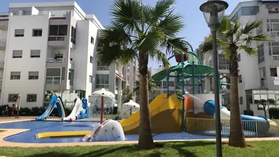 a water park with a playground with slides and palm trees at Appartement pied sur mer in Mohammedia