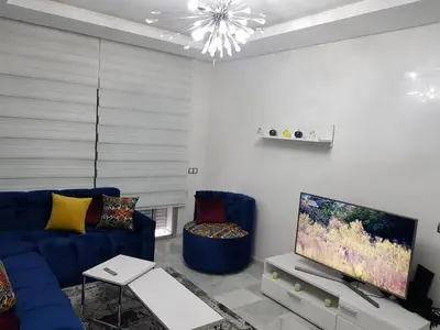 a living room with a blue couch and a tv at Appartement pied sur mer in Mohammedia
