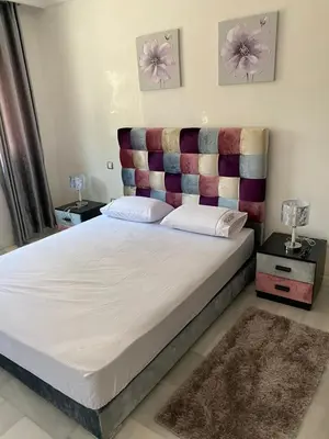 a bedroom with a large bed with a padded headboard at Appartement pied sur mer in Mohammedia