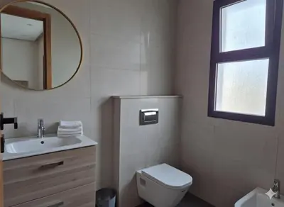 a bathroom with a toilet and a sink and a mirror at Grande villa sécurisée piscine privée in Dar Bouazza