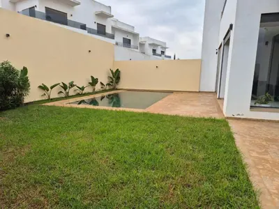 a backyard of a house with a swimming pool at Grande villa sécurisée piscine privée in Dar Bouazza