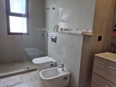 a white bathroom with a toilet and a sink at Grande villa sécurisée piscine privée in Dar Bouazza
