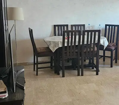 a dining room table with four chairs and a table with a white table cloth at Appartement au centre-ville, calme et lumineux in Casablanca