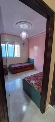 a bedroom with two beds and a chandelier at Appartement idéal pour familles in Temara