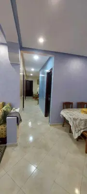 a room with a table and a blue wall at Appartement idéal pour familles in Temara