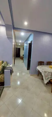 a room with a table and chairs and a blue wall at Appartement idéal pour familles in Temara