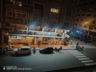 two cars parked in front of a building at night at Apparttement BOUCHRA in Casablanca
