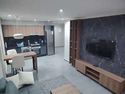 a living room with a large television and a kitchen at Un studio luxueux au centre de Casablanca in Casablanca