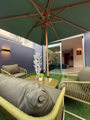a patio with a large green umbrella and a table at Élégant studio moderne Anoual Maarif Casablanca parfaitement équipé in Casablanca