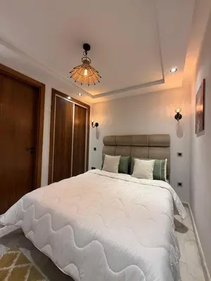 a bedroom with a large white bed and a chandelier at Élégant studio moderne Anoual Maarif Casablanca parfaitement équipé in Casablanca