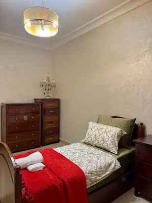 a bedroom with a bed with a red blanket and a dresser at Spacious athène apartment in Maarif