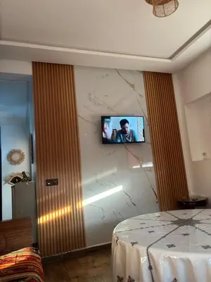 a room with a tv on a wall with a bed at Cozy Apartement next to the airport in Deroua