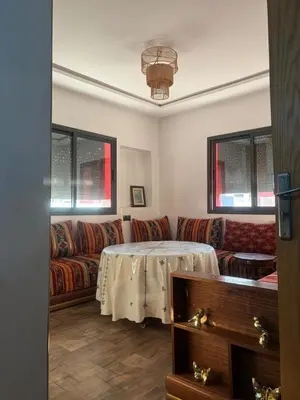 a living room with a table and a couch at Cozy Apartement next to the airport in Deroua