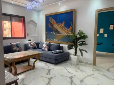 a living room with a blue couch and a painting at Appartement near the airport in Deroua