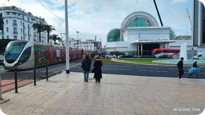 a group of people standing on a sidewalk near a train at Hassan in Rabat