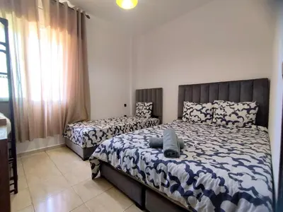 a bedroom with two beds and a large window at lodgeocean in Rabat