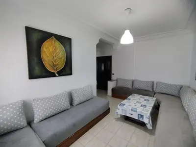 a living room with a couch and a leaf painting on the wall at lodgeocean in Rabat