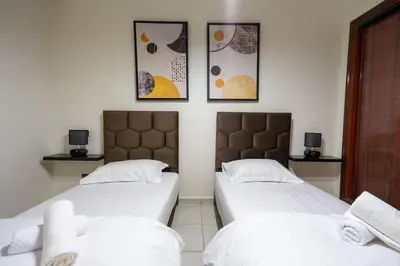 two beds in a room with three pictures on the wall at Bel appartement piscine & plage - Mohammedia in Mohammedia