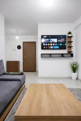 a living room with a couch and a tv on a wall at appartement familial a 5min de l'hôpital Mohamed 6 in Bouskoura