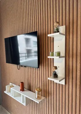 a television hanging on a wall with white shelves at Elegant studio with large terrace in Rabat