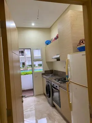 a small kitchen with a refrigerator and a stove at 2 bedroom apartment in a secured residence, minutes to beach in Bouznika