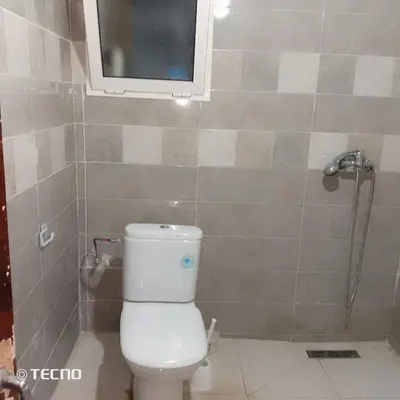 a bathroom with a toilet and a window and a shower at Hébergement en lit dans chambre et salle de bain partagées pour Hommes in Rabat