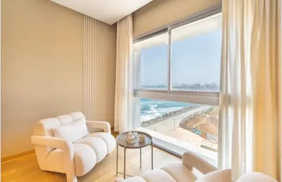 a living room with a white chair and a large window at Panoramic sea view high speed wi-fi central in Casablanca