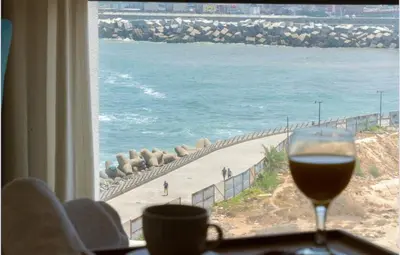 a glass of wine sitting on a table looking out at the beach at Panoramic sea view high speed wi-fi central in Casablanca