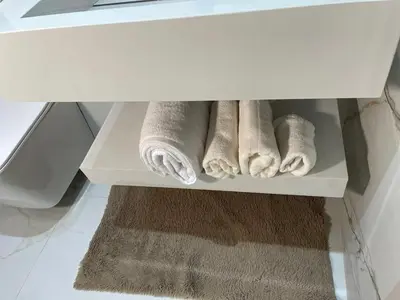 a white cabinet with towels and a rug in a bathroom at Premium Studio near Agdal Train Station in Rabat