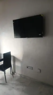 a black chair sitting in a room with a television on a wall at Relaxing Studio Stay with Pool, Balcony & Smart TV in Aïn Harrouda