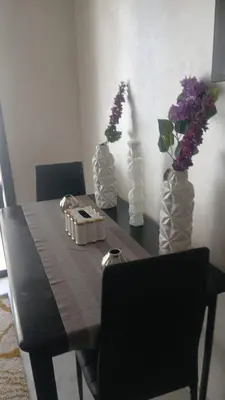 a dining room table with two vases with purple flowers at Relaxing Studio Stay with Pool, Balcony & Smart TV in Aïn Harrouda