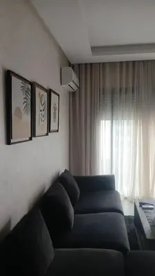 a living room with a blue couch and a window at Relaxing Studio Stay with Pool, Balcony & Smart TV in Aïn Harrouda
