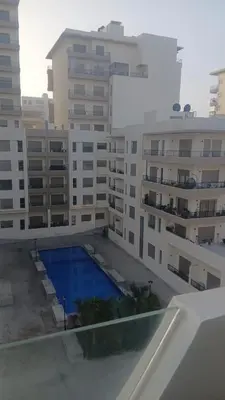 a building with a swimming pool in front of some buildings at Relaxing Studio Stay with Pool, Balcony & Smart TV in Aïn Harrouda