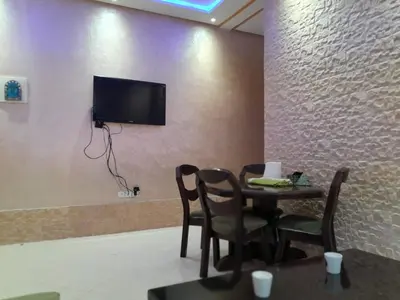 a dining room with a table and a tv on a wall at Magnifique T2 à Skhirat in Skhirat