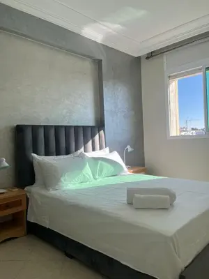 a bedroom with a large white bed with a window at Appartement lumineux en plein coeur de harhoura in El Harhoura