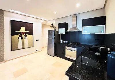 a kitchen with black appliances and a painting on the wall at Grand Studio Moderne au Centre, Parking Privé in Casablanca