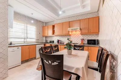 a kitchen with wooden cabinets and a table with chairs at Confort Urbain - Plein centre & Spacieux in Casablanca