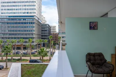 a chair on a balcony with a view of a city at Modern CFC Flat with Terrace Gym & City Views in Casablanca