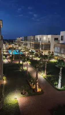 a courtyard with palm trees and a building at night at Residence blue beach Sidi Rahal in Sidi Rahal