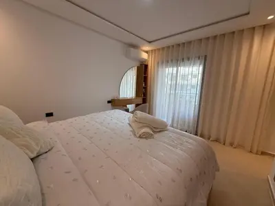 a bedroom with a white bed with a towel on it at appartement de Lux le clos in Bouznika