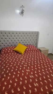 a bed with a red comforter with a yellow pillow at Stunning 2 bedrooms flat Palmier in Casablanca
