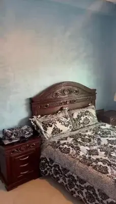 a bedroom with a bed with a wooden headboard and a dresser at Appartement al yakout 1 in Mansouria