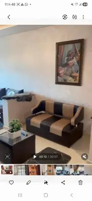 a living room with a couch and a picture on the wall at Appartement al yakout 1 in Mansouria