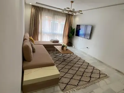 a living room with a couch and a table at Private Room,Piscine & Parking en cohabitation avec le hôte seulement à 6 min Airport MohamedV in Nouaceur