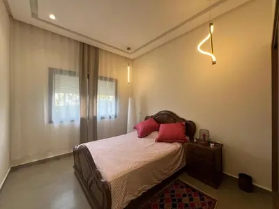 a bedroom with a bed with red pillows and a window at El Mansouria Mohammedia, Magic House T5 in Mansouria