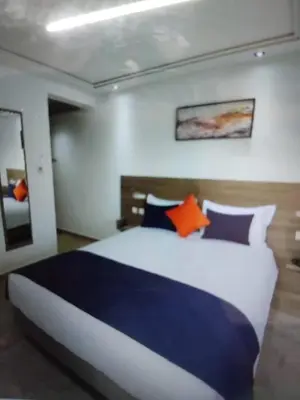 a bedroom with a large bed with blue and orange pillows at Belle chambre pour 2 sidi maarouf HOTEL in Casablanca
