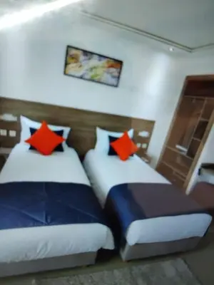 two beds in a hotel room with red pillows at Belle chambre pour 2 sidi maarouf HOTEL in Casablanca
